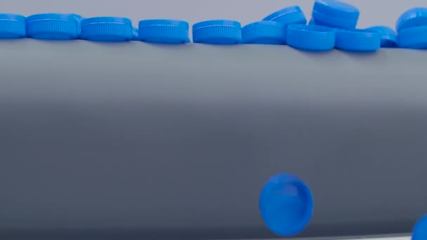 Molti tappi di plastica blu che cadono dal nastro trasportatore - rallentatore — Video Stock