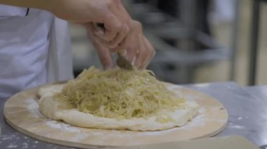 Baker, aşçı elleri ossetian lahana turtasını hazırlıyor.