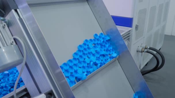 Viele blaue Plastikflaschenverschlüsse bewegen sich auf Förderband - Produktionslinie — Stockvideo