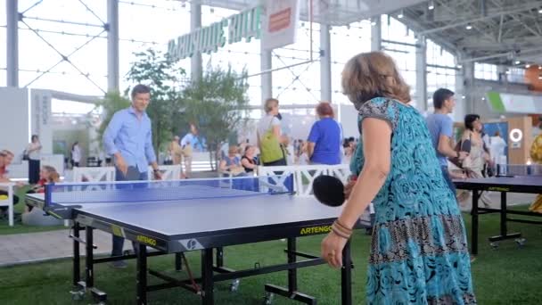 Jovem e mulher idosa jogando ping pong tênis de mesa na exposição esportiva — Vídeo de Stock