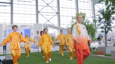 Bir grup insan spor sergisinde birlikte qigong egzersizi yapıyor.