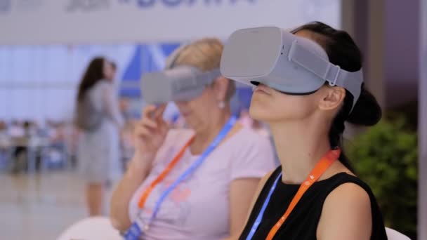 Dwie kobiety korzystające z zestawu słuchawkowego wirtualnej rzeczywistości na wystawie technologii VR — Wideo stockowe
