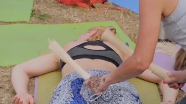 Kadın elleri dışarıda yoga festivalinde bambu çubuklarıyla masaj yapıyor.