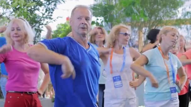 Äldre människor som tränar qigong tillsammans på idrottsmässan — Stockvideo