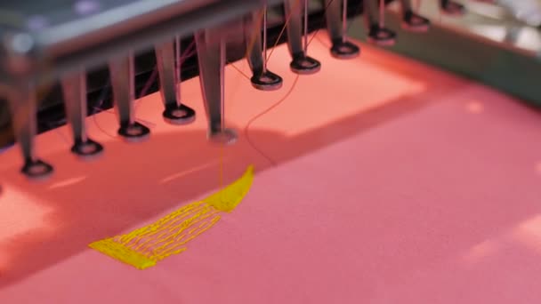 Embroidery machine making yellow Nike logotype on red fabric — Stock Video