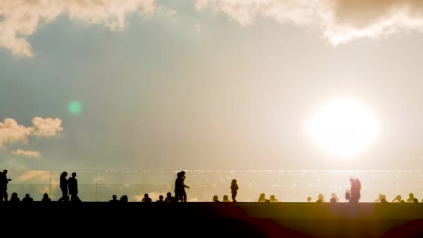 Nepoznatelní lidé siluety kráčející po mostě proti zatažené obloze západu slunce — Stock video