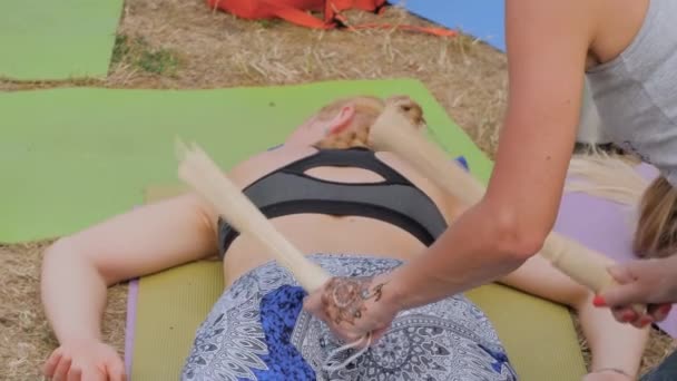 Manos de mujer haciendo masaje con palos de bambú en el festival de yoga al aire libre — Vídeo de stock