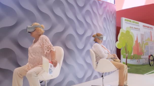 Duas mulheres idosas usando fones de ouvido de realidade virtual na exposição de tecnologia VR — Vídeo de Stock