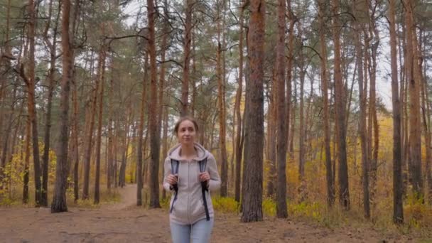 Přední pohled mladé ženy s batohem procházky v podzimním parku - steadicam shot — Stock video