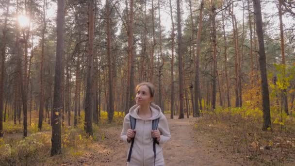 Vrouw met rugzak wandelen in het najaar park - steadicam schot, zonnebril fakkels — Stockvideo