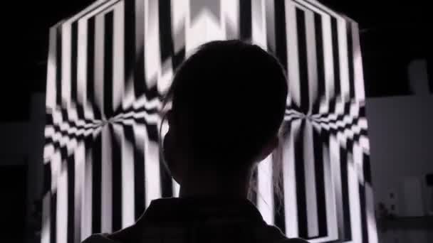 Kobieta patrząc na duży ekran sześcianu z obracającą się hipnotyczną iluzją optyczną — Wideo stockowe