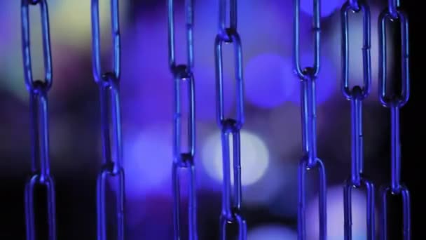 Närbild - blå metall kedja svänger mot färgglada bokeh bakgrund — Stockvideo