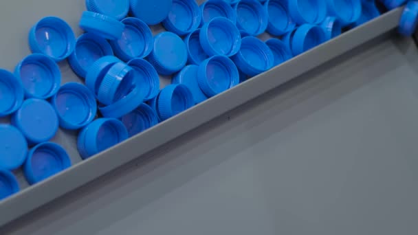 Viele blaue Plastikflaschenverschlüsse bewegen sich auf Förderband - Produktionslinie — Stockvideo