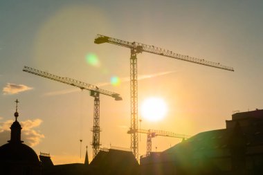 Gün batımına karşı kule vinçleri ve bitmemiş bina inşaatı