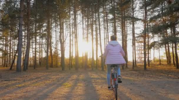 Ung kvinna rida cykel i höstens stadspark i solnedgången - slow motion — Stockvideo