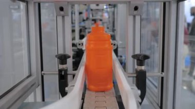 Sergide boş turuncu plastik bidonlar konveyör bandı üzerinde hareket ediyor