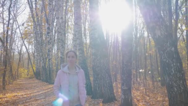 Mujer joven caminando en el parque de otoño - disparo steadicam, destellos de lentes de sol — Vídeos de Stock