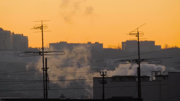 Tetti di vecchi edifici con antenne TV e fumo bianco contro il cielo alba — Video Stock