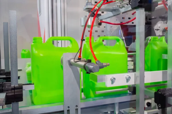 Empty green plastic jerry cans moving on conveyor belt at exhibition — Stock Photo, Image