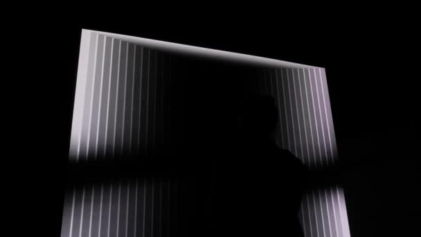 Жінка дивиться на великий куб екрану з обертовою гіпнотичною оптичною ілюзією. — стокове відео