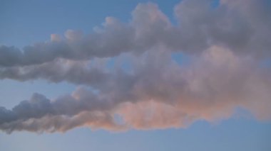 Fabrika bacasından beyaz duman, mavi günbatımına karşı baca.