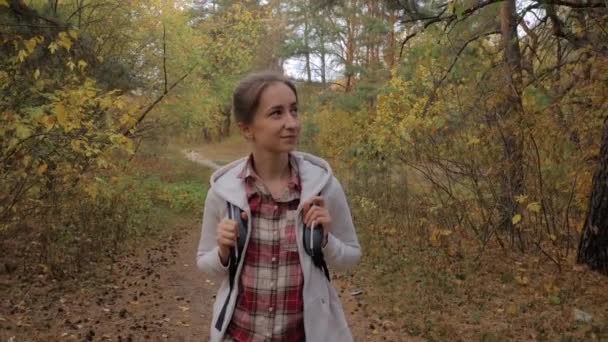 Frontansicht einer jungen Frau mit Rucksack beim Spazierengehen im Herbstpark - Steadicam-Aufnahme — Stockvideo