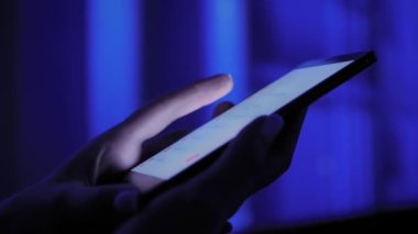 Sergide renkli ışıklandırmalı akıllı telefon kullanan kadın - yakın çekim