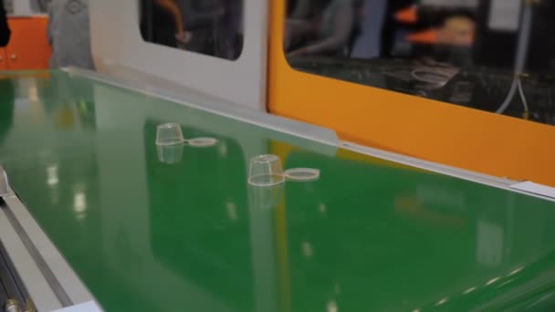 Vasos de plástico vacíos moviéndose en la cinta transportadora en la exposición — Vídeo de stock