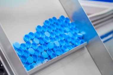 Birçok mavi plastik şişe kapağı taşıma bandı üzerinde hareket ediyor - üretim hattı