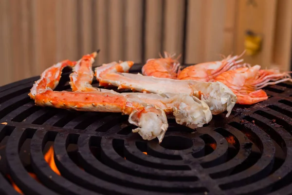 Process of cooking fresh red crab legs and prawns on grill