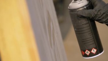 Yavaş çekim: Adam graffiti festivalinde tahta yüzeyden boya püskürtüyor.