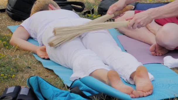 Férfi kéz csinál masszázs a nő bambusz rúd szabadtéri jóga fesztivál