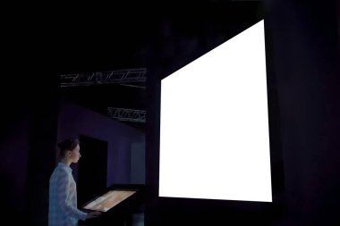 Büfe kullanan ve karanlık odadaki büyük beyaz ekrana bakan bir kadın.