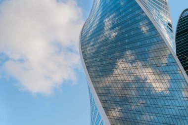 Beyaz bulutların yansıması ve mavi gökyüzü modern gökdelenlerin cam duvarında