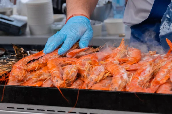 Chef cooking fresh red langoustine shrimps, prawns on grill at summer local food