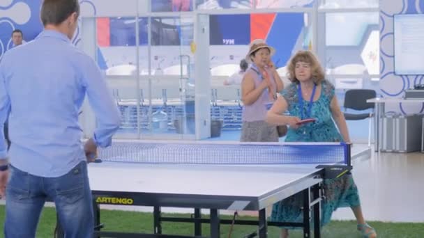 Ung man och äldre kvinna spelar pingis bordtennis på sportutställning — Stockvideo