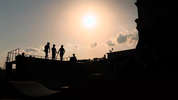 青少年在日落时在滑板车上展示跳高技巧的轮廓-慢动作 — 图库视频影像