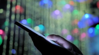 Sergide renkli ışıklandırmalı akıllı telefon kullanan kadın - yakın çekim