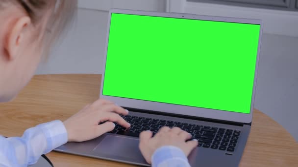 Donna che utilizza laptop grigio con display verde vuoto sul tavolo - vista a spalla — Video Stock