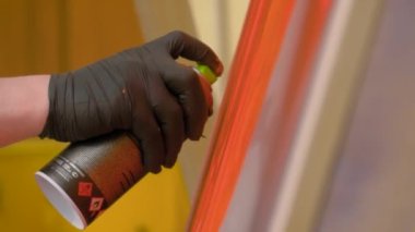 Yavaş çekim: Adam graffiti festivalinde tahta yüzeyden boya püskürtüyor.