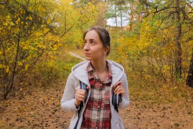 Sırt çantalı genç bir kadının sonbahar parkında yürüyüşü.