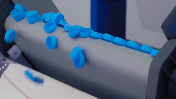Γραμμή παραγωγής - πολλά μπλε πλαστικά καπάκια μπουκαλιών που πέφτουν από ιμάντα μεταφοράς — Αρχείο Βίντεο