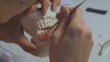 Diş teknisyeni diş protezleriyle çalışıyor. Görüntüyü kapat.