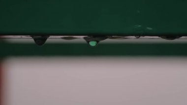 Metal çatı deposundan ağır yağmur damlaları düşüyor. Yakın çekim, yavaş çekim.