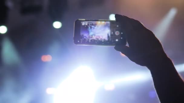 Le mani dell'uomo registrano il video del concerto di musica dal vivo con lo smartphone - primo piano — Video Stock