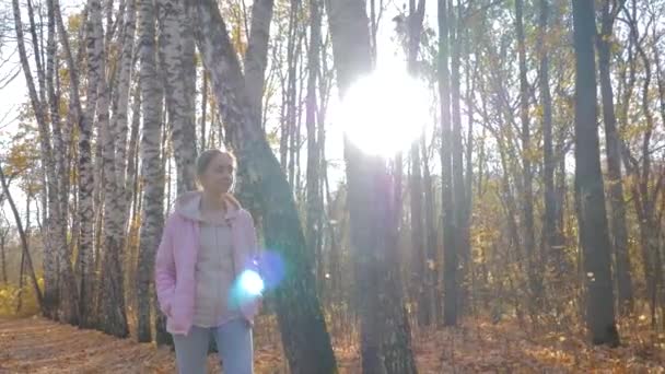 Jonge vrouw wandelen in de herfst park - steadicam schot, zonnebril fakkels — Stockvideo