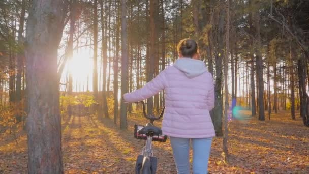 Ung kvinna promenader med cykel i höst barrskog - slow motion — Stockvideo