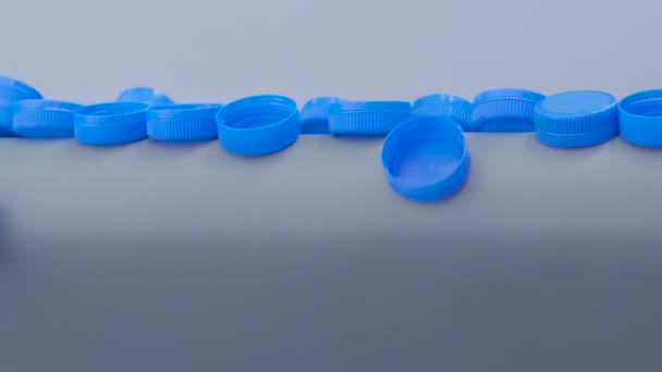 Langzame beweging: blauwe plastic flessendoppen vallen van transportband — Stockvideo