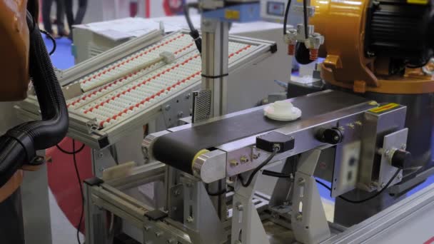 Pick and place robotic arm manipulator moving plastic detail on conveyor belt — Stock Video