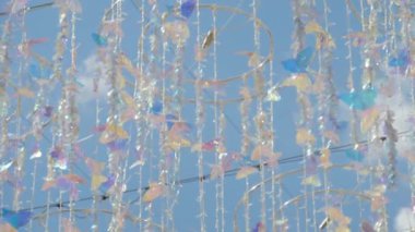 Parlak asılı kelebek süslemesi rüzgarda sallanıyor bulutlu mavi gökyüzüne karşı